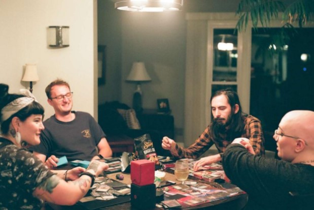 People playing commander around a table looking happy
